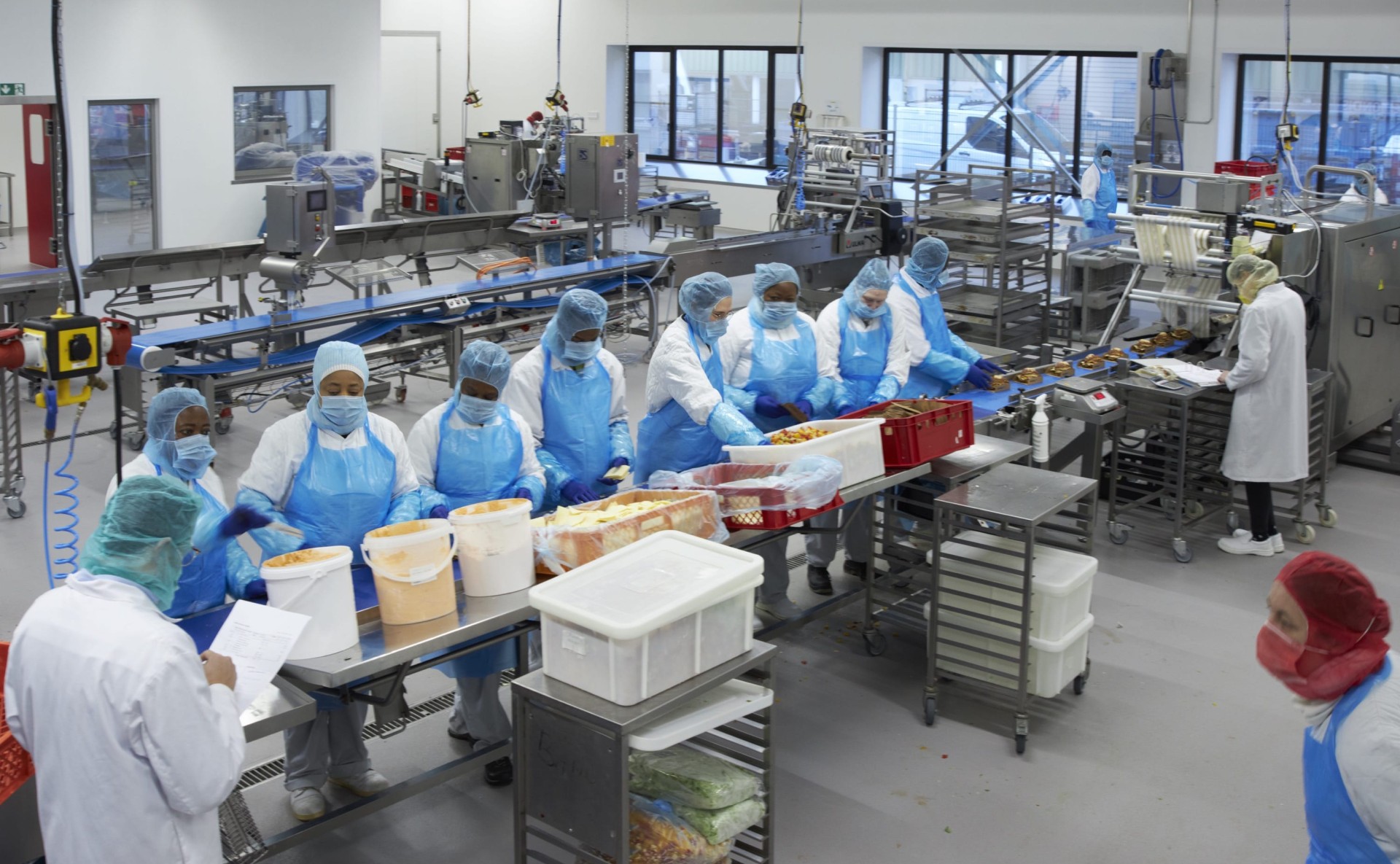 Produktionshalle mit mehreren Mitarbeitenden in Schutzkleidung.